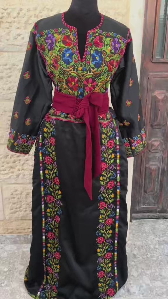 Elegant black dress featuring vibrant hand-embroidered details, accentuated with a stylish belt for a flattering fit.